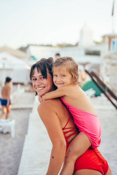 若いですお母さん与え娘piggyback乗り物オンザビーチ - 写真・画像
