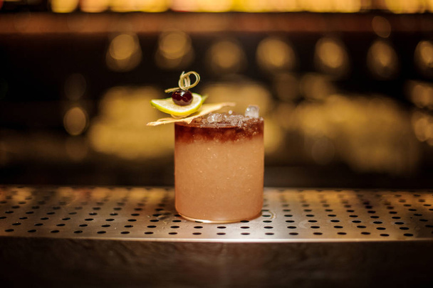 Elegante bicchiere da cocktail ripieno di gustosa bevanda alcolica dolce con fette di ghiaccio e frutta
 - Foto, immagini