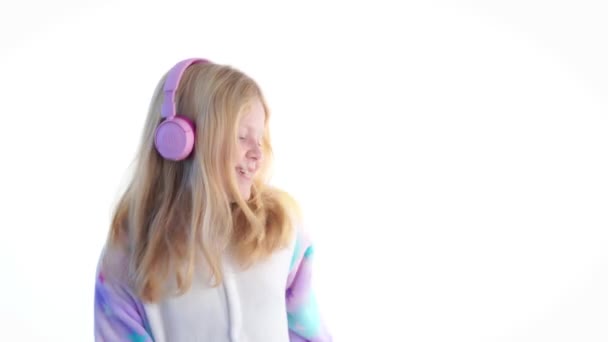 moda moderna - hermosa chica rubia escucha música con auriculares y bailando sobre un fondo blanco en pijama kigurumi - aislado en blanco
 - Imágenes, Vídeo