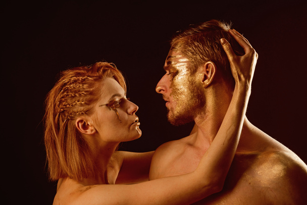 Sexy couple with golden body art makeup isolated on black. Gold spa and skincare treatment. Man and woman relations. Golden collagen mask and beauty. 24K Gold. Erotic games of couple in love - Valokuva, kuva