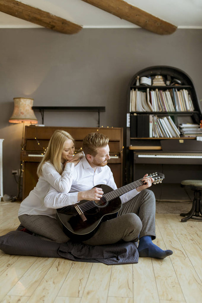 Man playing acoustic guitar for his young beautiful woman - Photo, Image