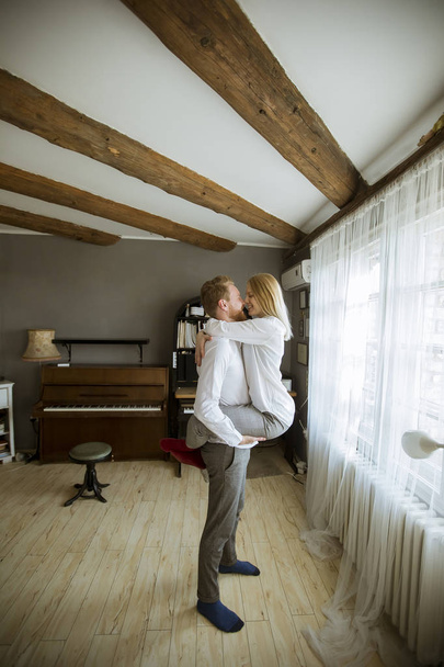 Happy en liefdevolle jonge paar kussen op de kamer - Foto, afbeelding