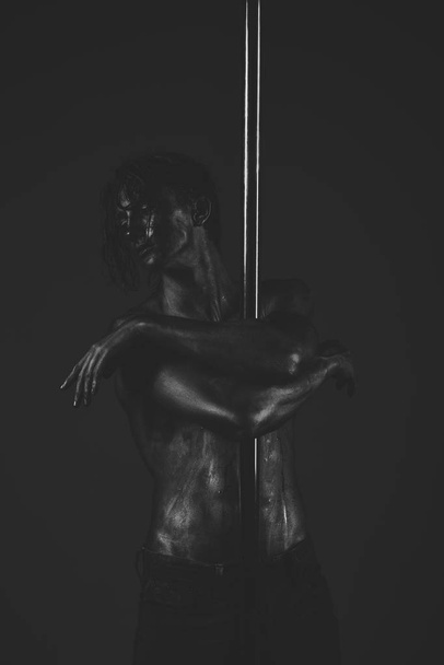 Young strong pole dance man on dark background. - Photo, Image