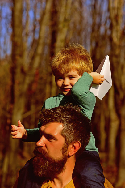Father and son launch paper plane in park. Father and son play together outdoor. Grab fun with travel - Φωτογραφία, εικόνα