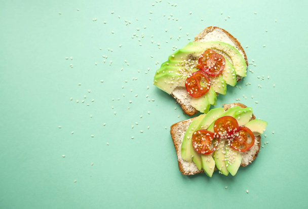 Flat lay of delicious toasts with sliced avocado, tomatoes and sesamum seeds on blue background with copyspace. Healthy food concept. - Foto, immagini