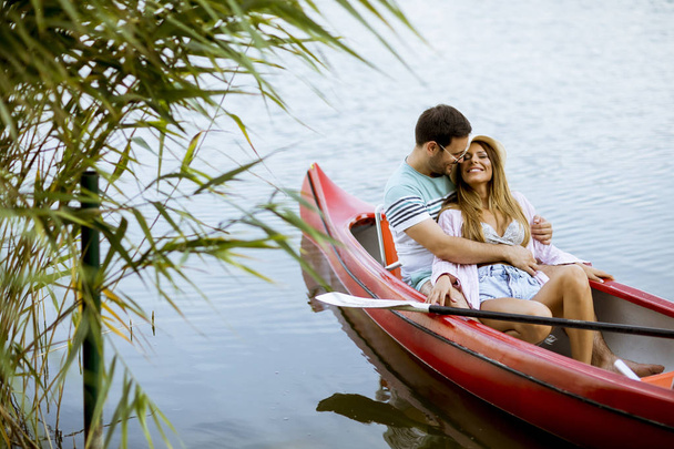 Loving couple rowing on the calm lake at summer day - Foto, afbeelding