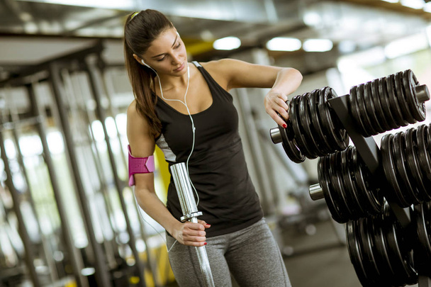 Красивая молодая женщина тренируется с весовым оборудованием в спортзале
 - Фото, изображение