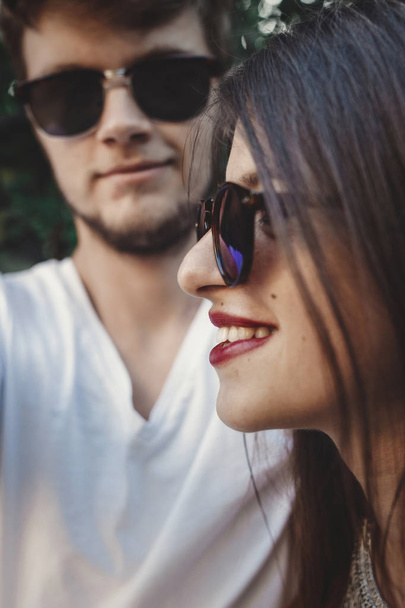 Stylish hipster couple in sunglasses smiling and making cool selfie. Happy family couple in love making self portrait and laughing in evening summer city. Vacation  and travel together - Photo, Image