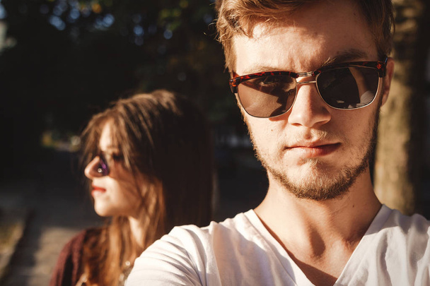 Stylish hipster couple making selfie and embracing in sunlight. Happy family couple in love making self portrait and posing in evening summer city. Vacation  and travel together - Valokuva, kuva