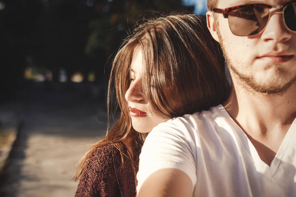 Stylish hipster couple making selfie and embracing in sunlight. Happy family couple in love making self portrait and smiling in evening summer city. Vacation  and travel together - 写真・画像
