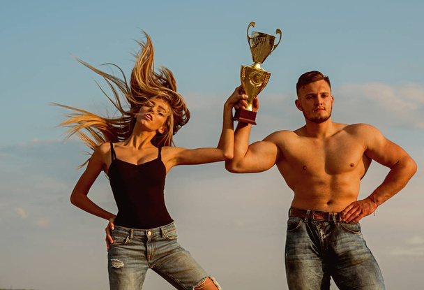 Champions celebrate victory. Athletic champions with golden cup on blue sky. Champions won competition. Woman and man champions. Winners never quit and quitters never win - Photo, Image