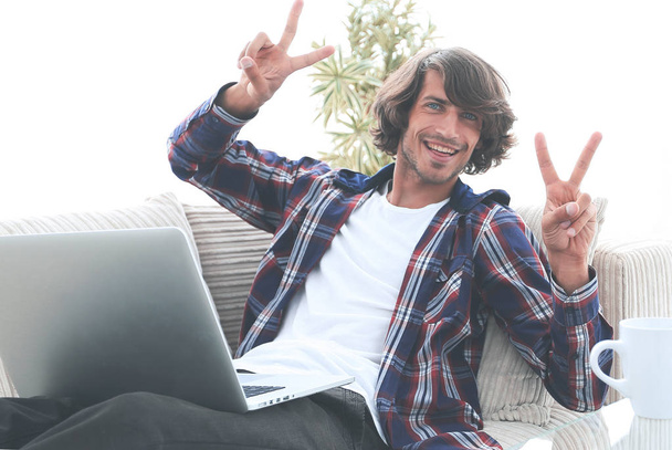 happy guy with a laptop showing a winning gesture. concept of success. - Foto, afbeelding