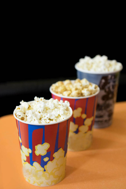 Photos of popcorn in cups. Popcorn near the cinema. Watching a movie, a cartoon with popcorn. - Фото, изображение
