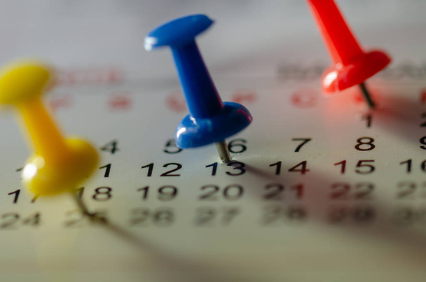 Alfileres azules bordados en un calendario el día 13 con enfoque selectivo
 - Foto, Imagen