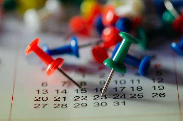 Geborduurde kleur pinnen op een kalender op 23 en 15e met selectieve aandacht - Foto, afbeelding