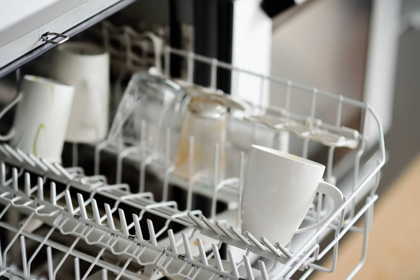 Open dishwasher with dirty crockery in the modern kitchen. Close-up. Domestic appliances for help and time saving in housework. - Φωτογραφία, εικόνα