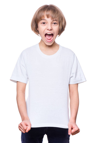 White T-shirt on Teen Girl. Cute screaming Child pointing on Copy-Space, isolated on white background. Concept of childhood and fashion or advertisement design. Mock up template for design print. - Foto, imagen