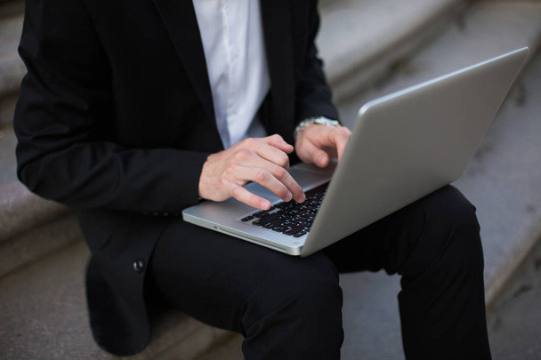 Close up businessman in classic black suit working on laptop outdoor - Foto, Imagen