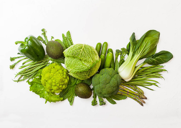 Assorted green toned raw organic vegetables on white background. Avocado, cabbage, broccoli, cauliflower and cucumber with trimmed and mung beans, pak choi, loose pepper and lettuce - Photo, Image