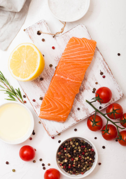 Plastic container with fresh salmon slice with oil tomatoes and lemon on stone kitchen background - Photo, image