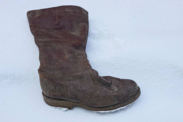 une vieille et sale botte en cuir marron se tient dans une neige blanche
 - Photo, image