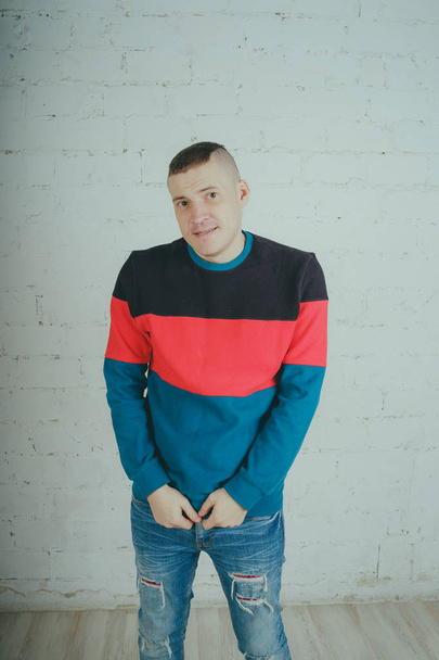 Handsome guy posing against a brick wall. Crazy man in striped sweatshirt - Photo, Image
