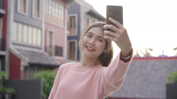 Alegre bela jovem asiático mochileiro blogger mulher usando smartphone tirar selfie enquanto viaja em Chinatown, em Pequim, China. Estilo de vida mochila turista viagem férias conceito
. - Filmagem, Vídeo