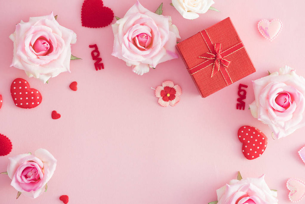 Ystävänpäivä lahjapaketti punaisella sydämellä ja ruusuilla vaaleanpunaisella taustalla
. - Valokuva, kuva