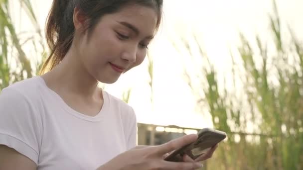 fröhliche asiatische Touristenbloggerin, die ihr Smartphone zur Orientierung benutzt und auf der Lagekarte sucht, während sie auf der Straße in der Innenstadt unterwegs ist. Lifestyle Rucksack touristisches Reisekonzept. - Filmmaterial, Video