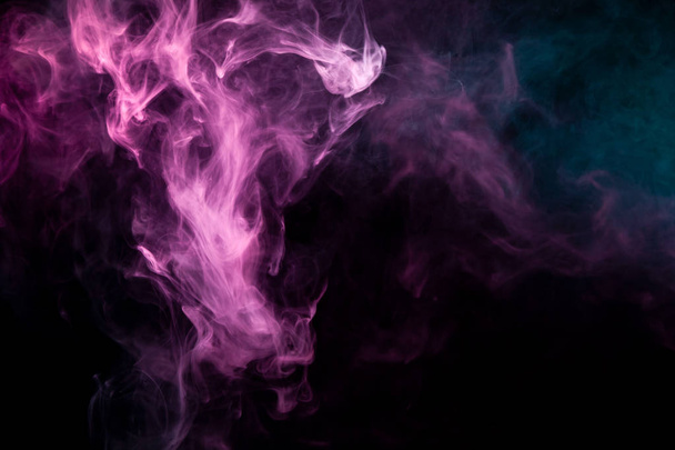 Humo de color rosa y azul sobre un fondo negro aislado. Antecedentes del humo del vap
 - Foto, imagen