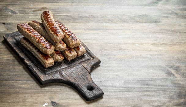 Grilled sausages on the board. On a wooden background. - Photo, Image