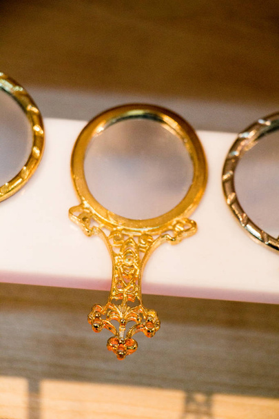 Kis dekoratív arany színű kézi tükör a polcon - Fotó, kép