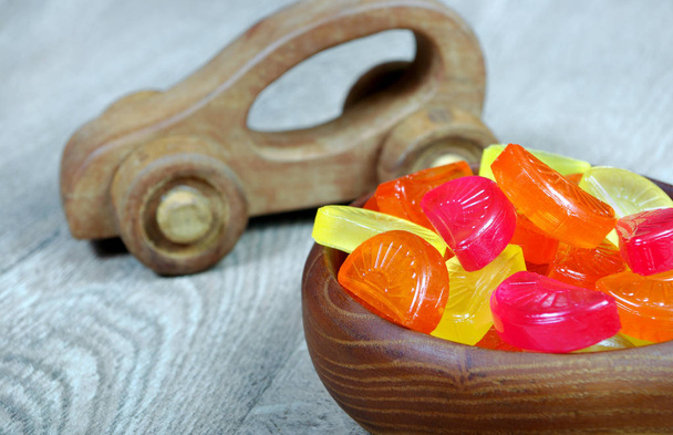 multicolored candies in a wooden plate. sweets and toys in the childs playroom - Photo, Image