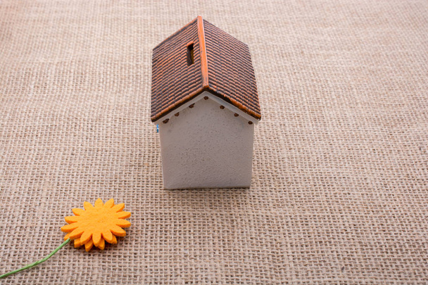 Фальшива квітка біля модельного будинку на коричневому кольоровому фоні
 - Фото, зображення