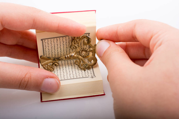Hand holding Key en Islamitische Heilige Boek Koran in mini-formaat - Foto, afbeelding