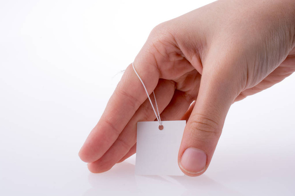 Hand holding a white tag with string - Photo, image