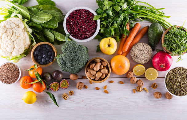 gesunde Ernährung: Obst, Gemüse, Samen, Superfood, Getreide, Blattgemüse auf schwarzem Holzhintergrund mit Kopierraum, Ansicht von oben. - Foto, Bild