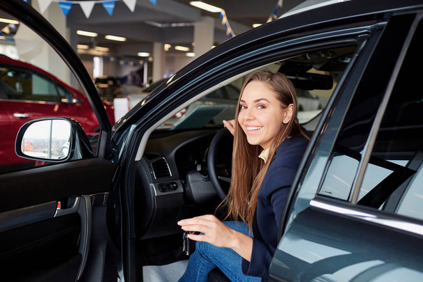 A female driver smiles and holds car keys. - Фото, изображение