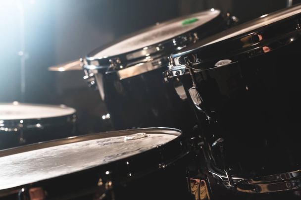 Closeup view of a drum set in a dark studio. Black drum barrels with chrome trim. The concept of live performances - Fotografie, Obrázek