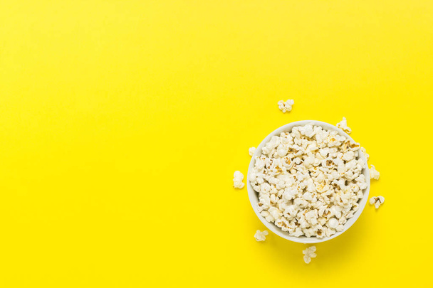 Bowl with popcorn on a yellow background. Flat lay, top view - Foto, afbeelding