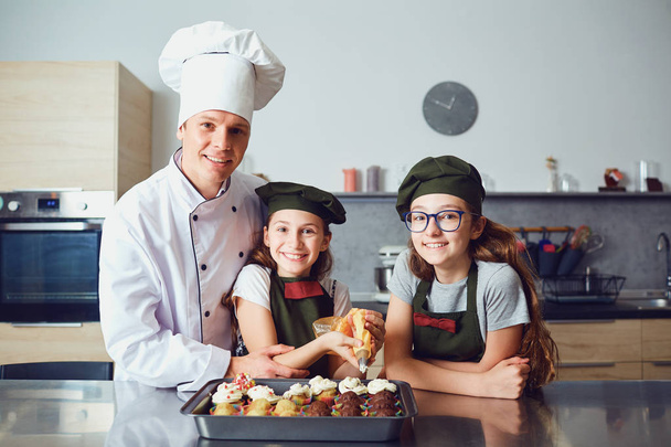 Pastry-cook with girls children prepare cookies in the kitchen. - Foto, Imagem