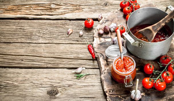 Cooked tomato sauce with garlic, spices and herbs. On a wooden background. - Photo, image