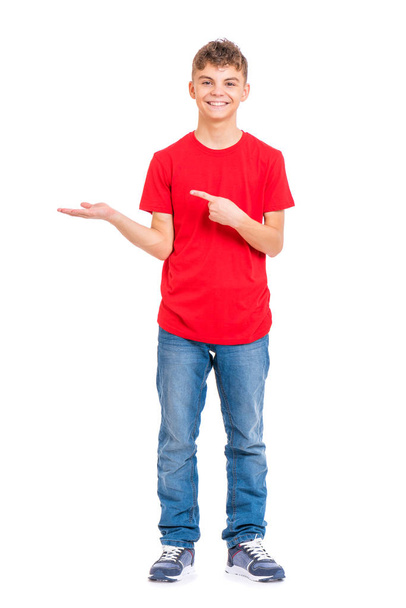 Full length portrait of teen boy holding something imaginary on palm, isolated on white background. Funny teenager showing copyspace on palm. Handsome child looking at camera and smiling. - Foto, Bild