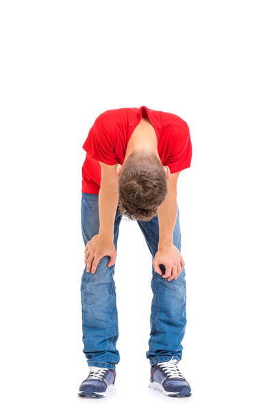 Full length portrait of tired teen boy, isolated on white background. Sad teenager grounded looking down, posing at studio.  - Valokuva, kuva