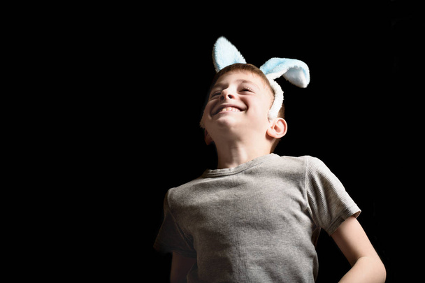 Engraçado menino loiro feliz em seus ouvidos orelhas salta em um fundo preto
 - Foto, Imagem