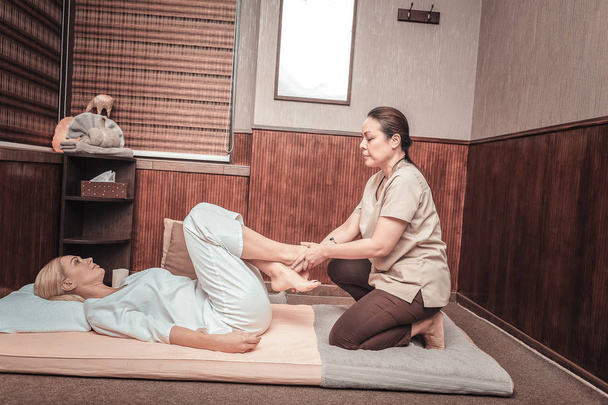 Nice skilled woman putting her clients legs together - 写真・画像