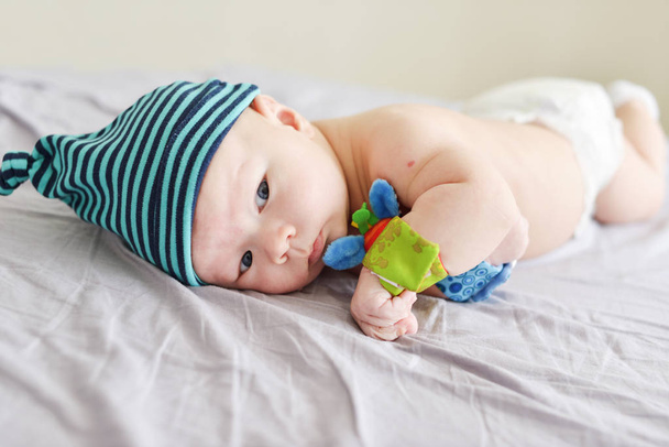 baby with bracelet toys on hands laying on the bed - Foto, imagen