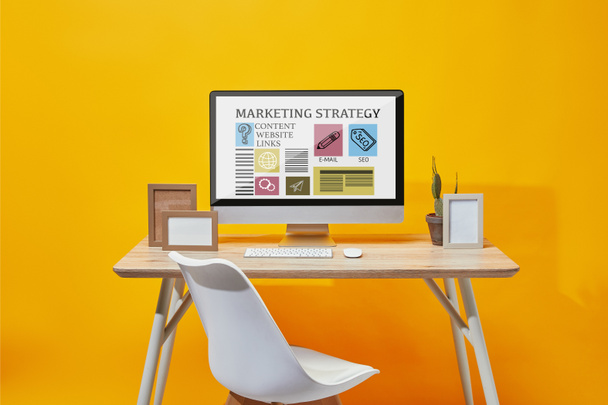 Мбаппе с сайтом маркетинговой стратегии на экране за деревянным столом на желтом фоне
 - Фото, изображение