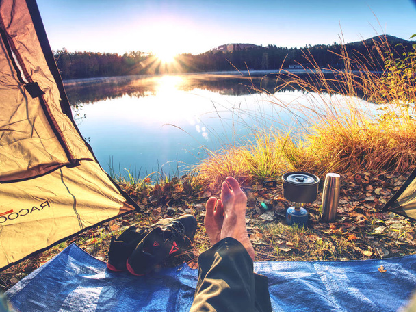 Vista sul corpo dell'uomo in tenda da campeggio al lago in bella mattina. Godetevi la libertà nella natura pura
. - Foto, immagini