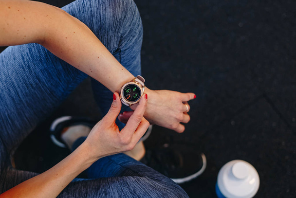 koncept zdravého životního stylu. fitness žena po trénink relace kontroluje výsledky na smartwatch podrobně fitness app. atletka na sobě sport tracker náramek ramenem - Fotografie, Obrázek